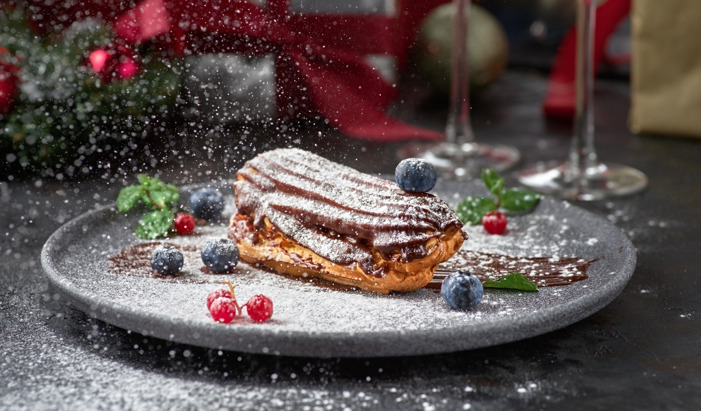 Вкусное пирожное на тарелке с сахарной пудрой и ягодами