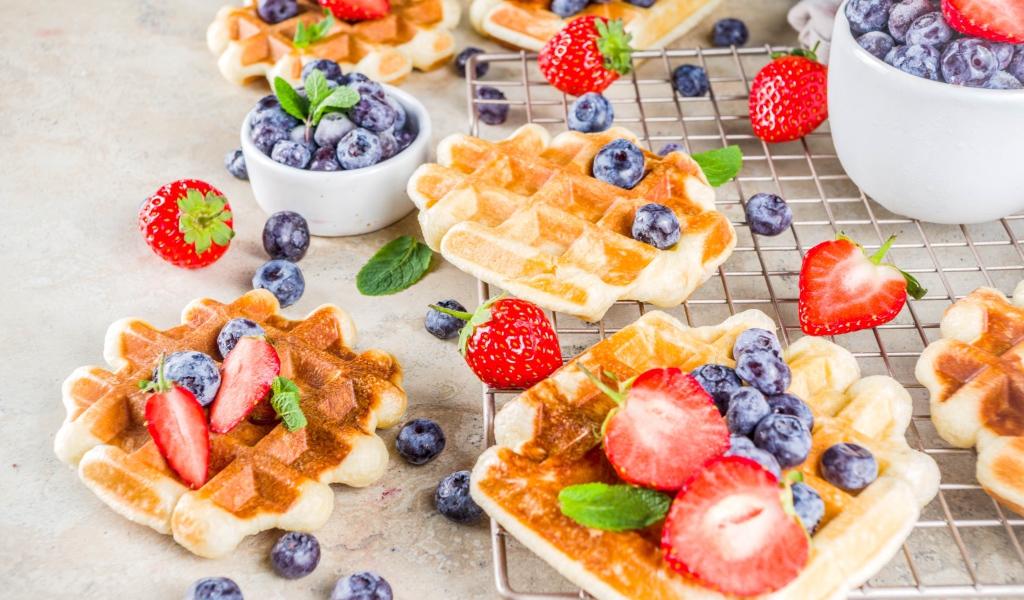 Вкусные сладкие вафли на столе с ягодами черники и клубники