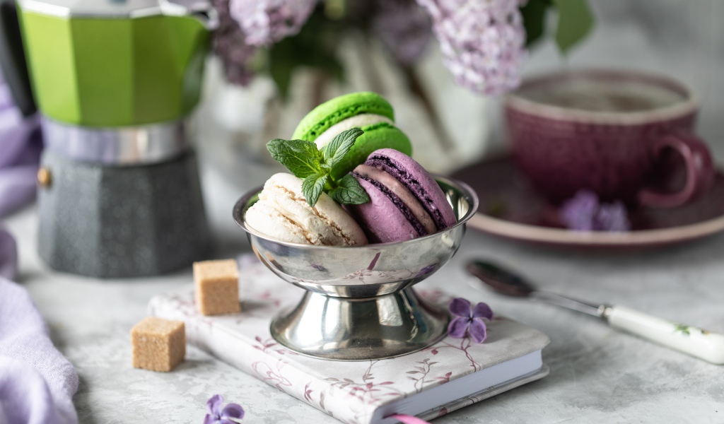 Три печенья макарун на столе с блокнотом