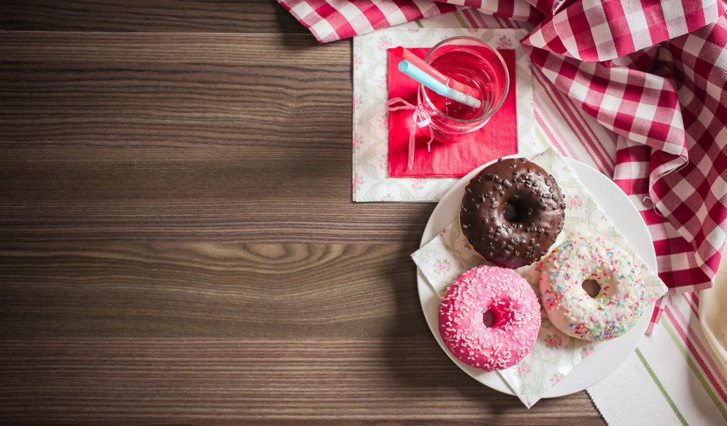 Три сладких пончика с глазурью на столе с лимонадом