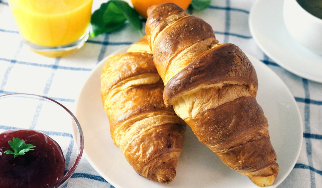 Два круассана на столе с джемом и соком