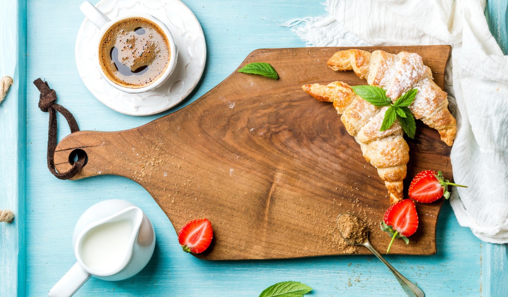 Деревянная доска на столе с круассанами и чашкой кофе