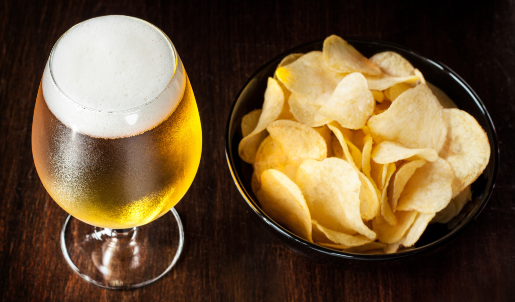 Миска с чипсами на столе с бокалом пива 