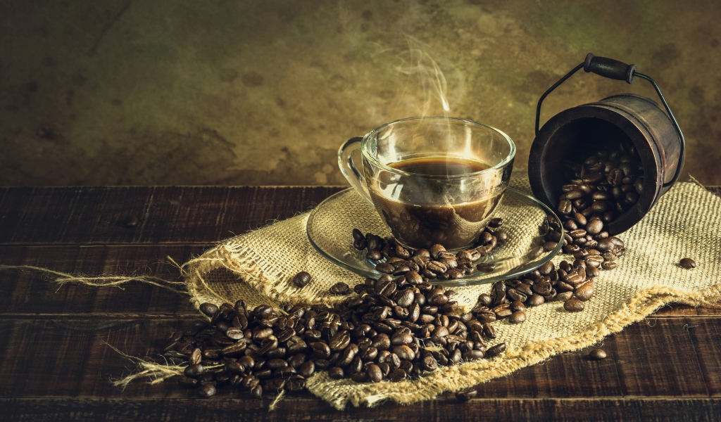 Чашка горячего крепкого кофе на столе с зернами