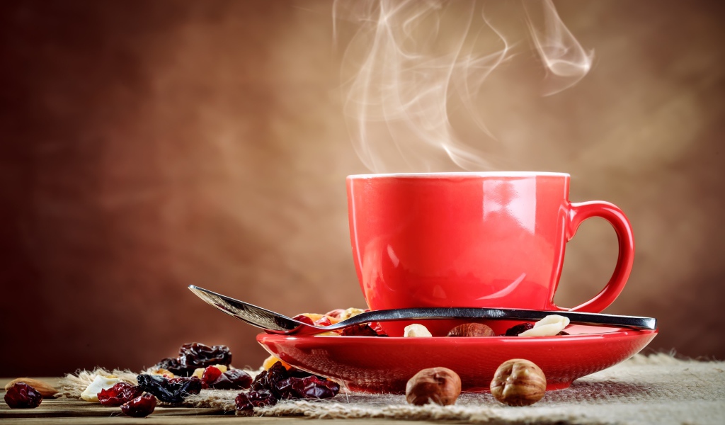 Ароматное горячее кофе в красной чашке на столе с сухофруктами