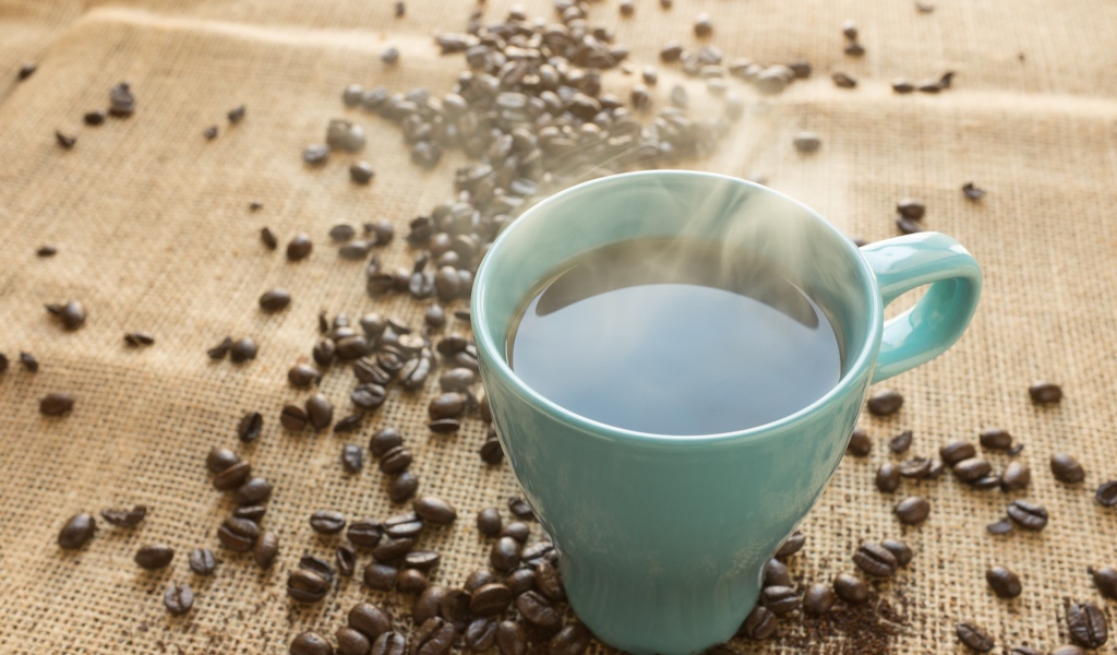 Голубая чашка кофе на столе с зернами