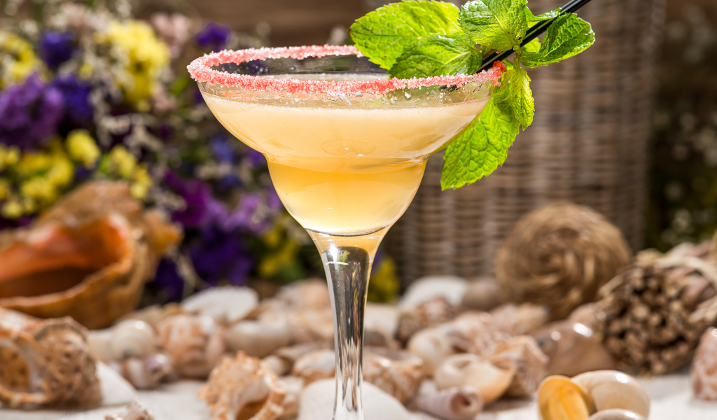 Коктейль с мятой в бокале на столе с ракушками 