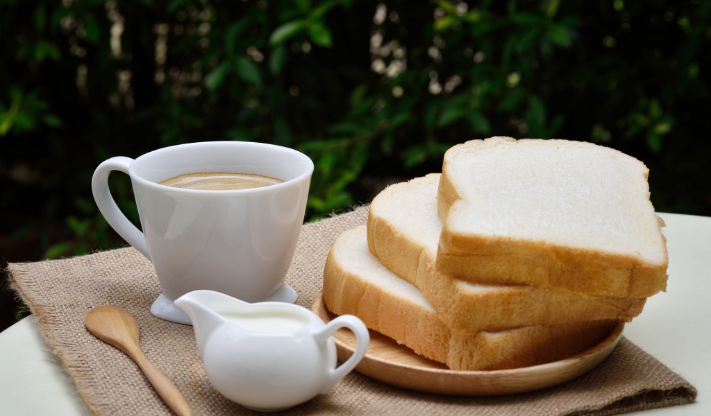 Кофе с молоком на столе с хлебом