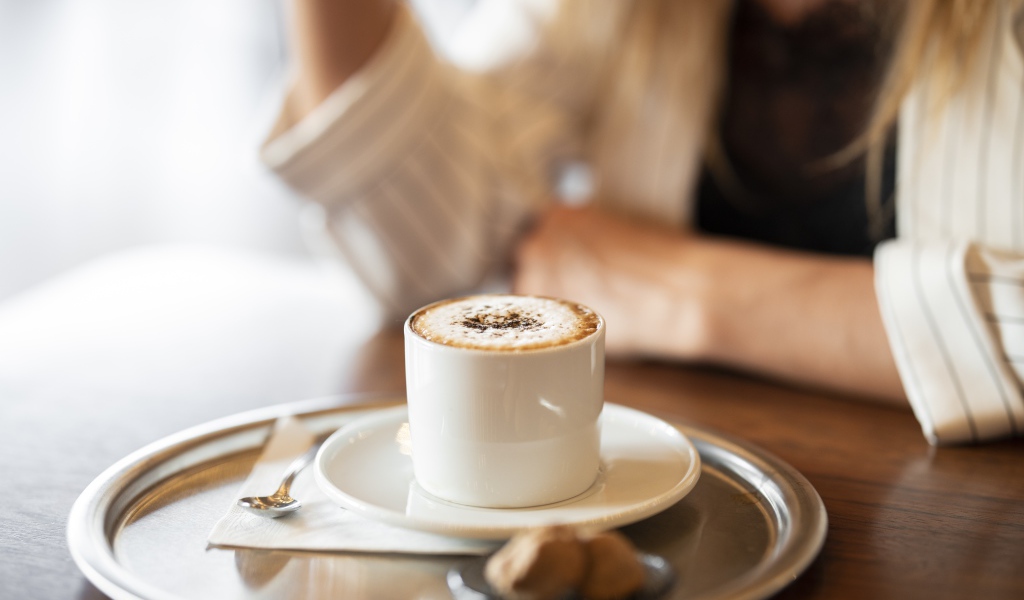 Чашка капучино с корицей на столе в кафе