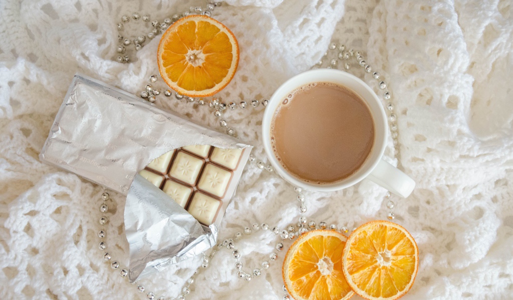 Чашка какао, шоколад и апельсин на белом пледе