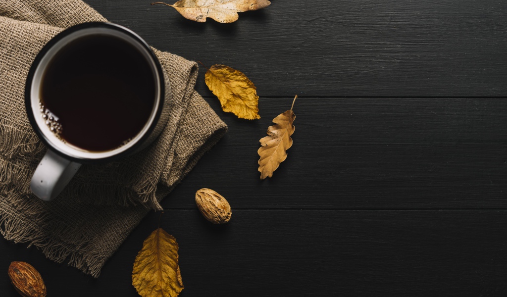 Чашка кофе на черном столе с листьями