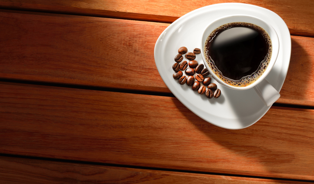 Чашка кофе на тарелке с зернами на деревянном столе