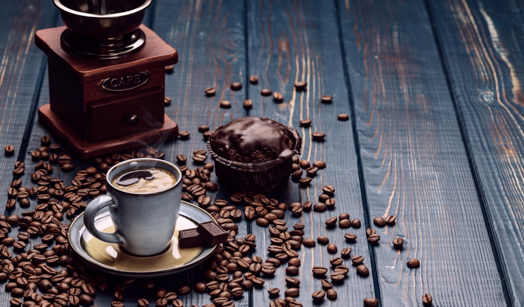 Чашка кофе на столе с шоколадным кексом и кофемолкой