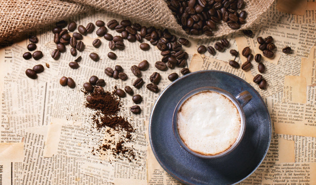 Чашка кофе на столе со старыми газетами и зернами