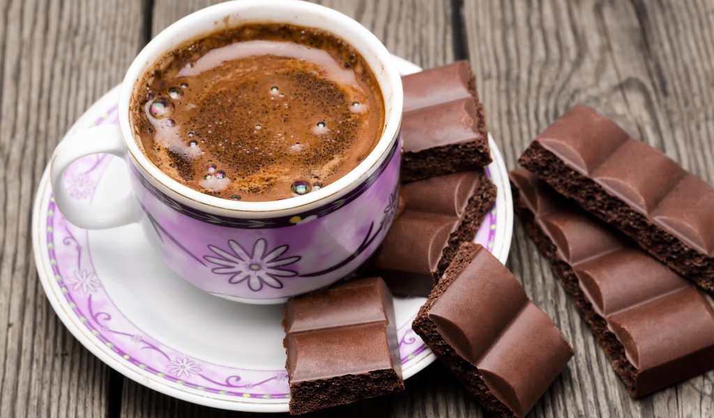 Чашка кофе на столе с кусочками шоколада