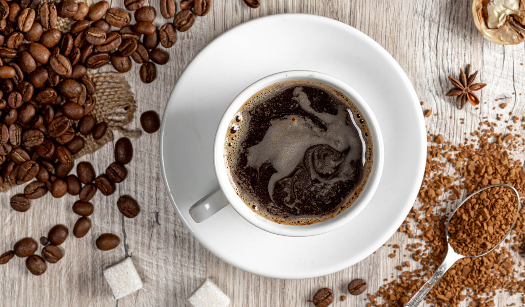 Чашка кофе на столе с сахаром и кофейными зернами