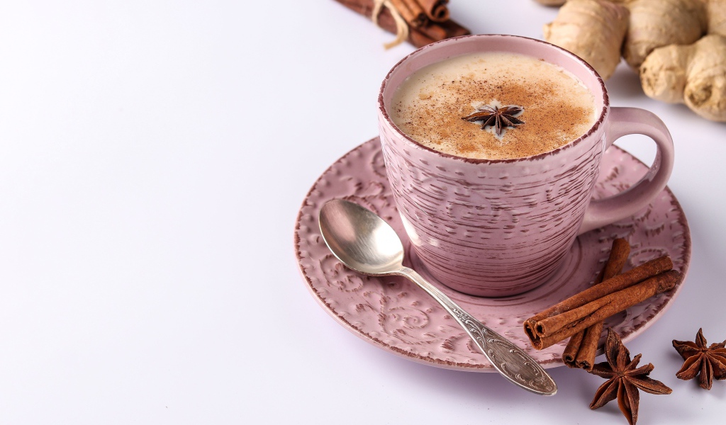 Чашка кофе на столе с корицей, бадьяном и  имбирем на белом фоне 