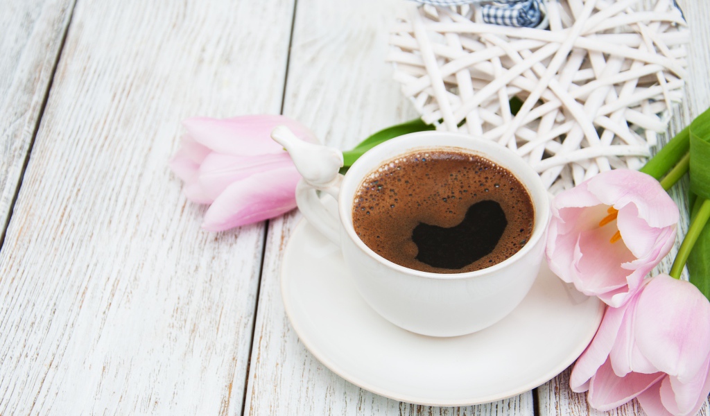 Чашка кофе на столе с розовыми тюльпанами и плетеным сердцем