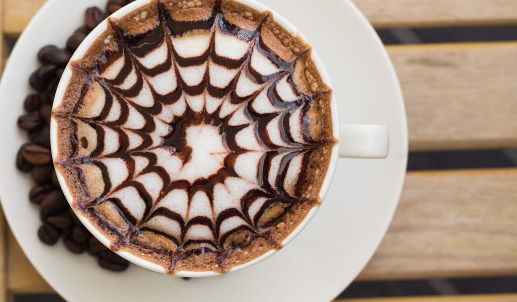 Чашка кофе с рисунком на пене на столе