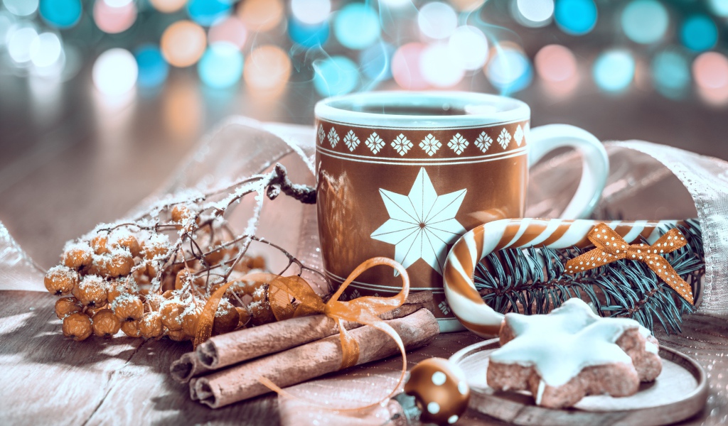 Чашка горячего кофе на столе с корицей и печеньем и веткой рябины