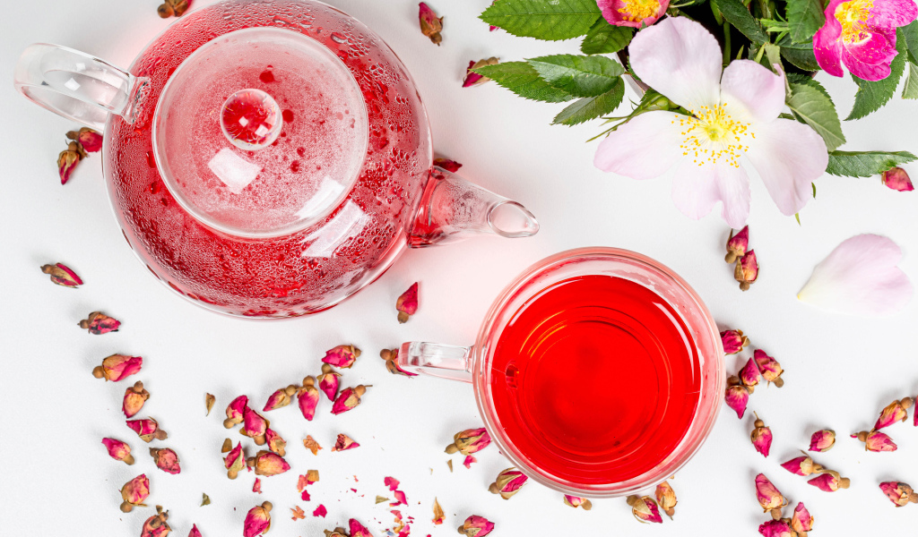 Свежий чай с шиповника в стеклянной чашке на столе с чайником