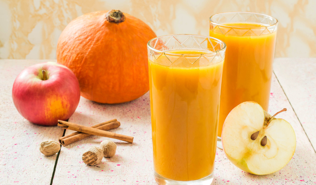 Свежевыжатый сок в стаканах на столе с фруктами