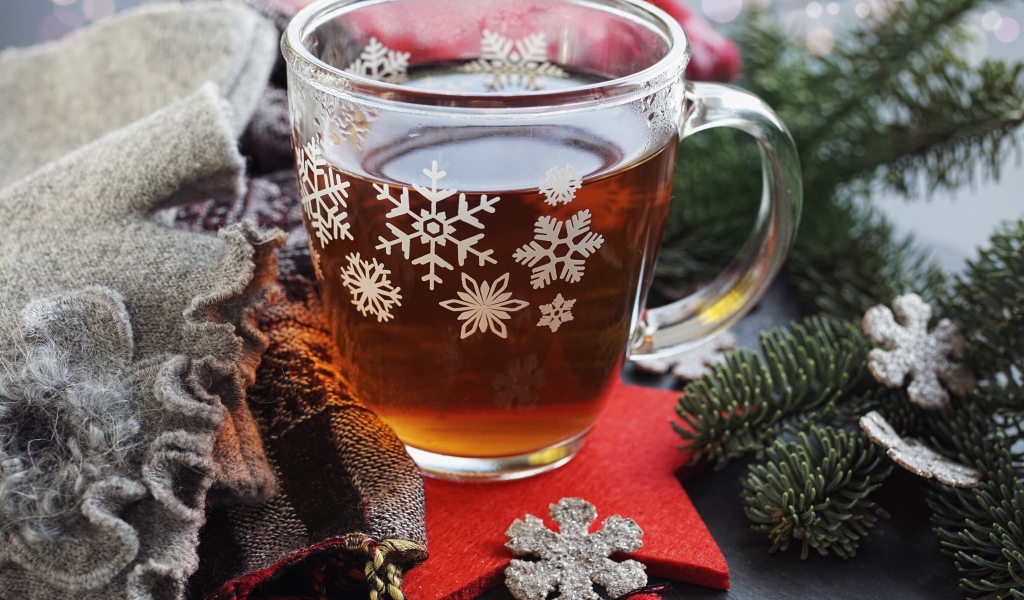 Стеклянная чашка чая на столе с ветками ели и шарфом 