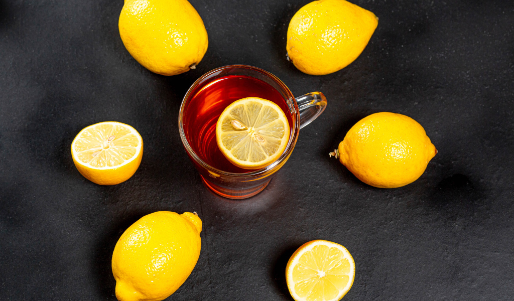 Стеклянная чашка чая с лимоном на сером столе 