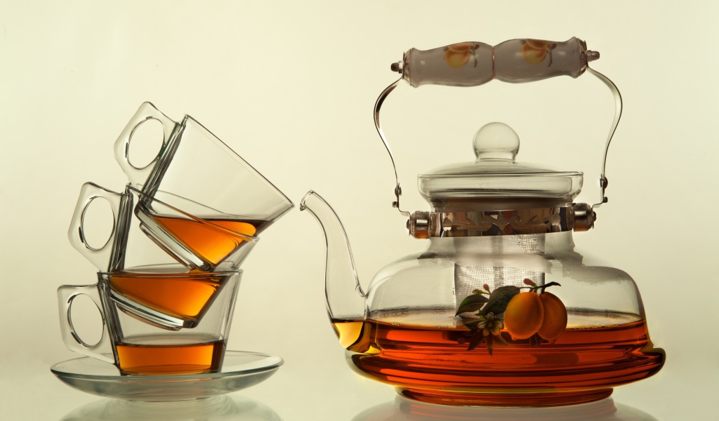 Стеклянный чайник с чашками на белом фоне