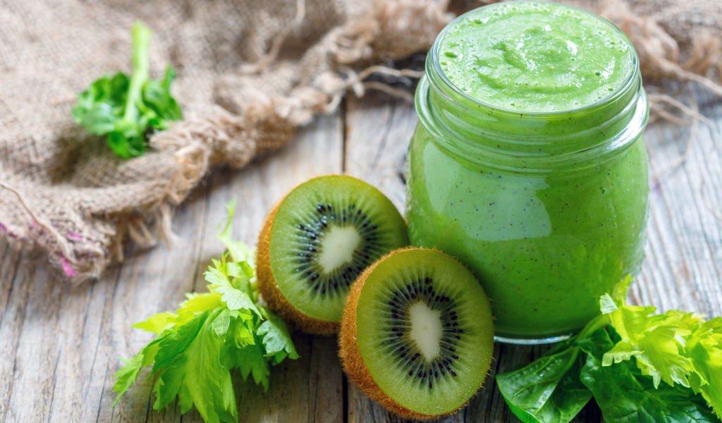 Зеленое смузи на столе с киви и зеленью 