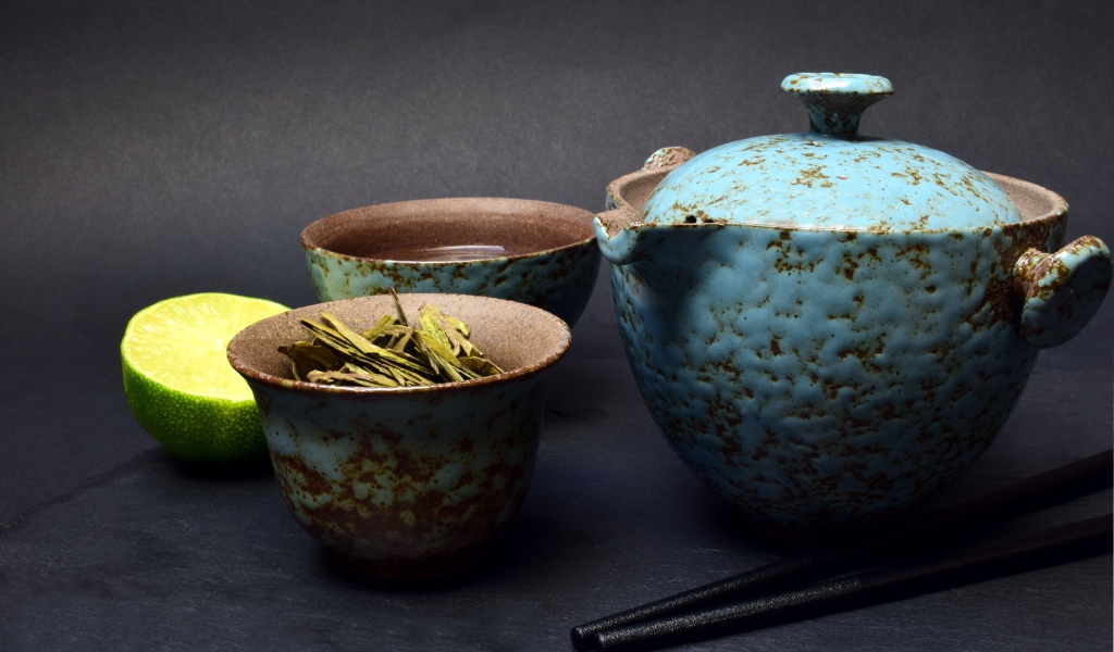 Зеленый чай на столе с посудой и лаймом