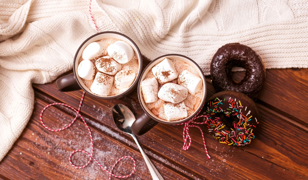 Горячий какао с маршмеллоу с пончиками на столе 