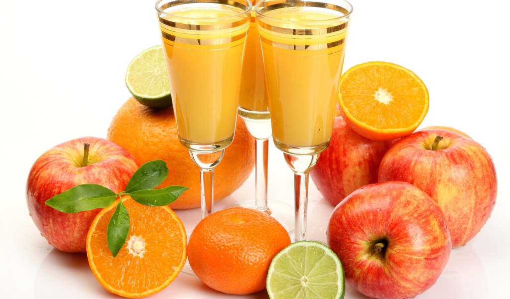 Сок в фужерах на столе с яблоками и мандаринами 