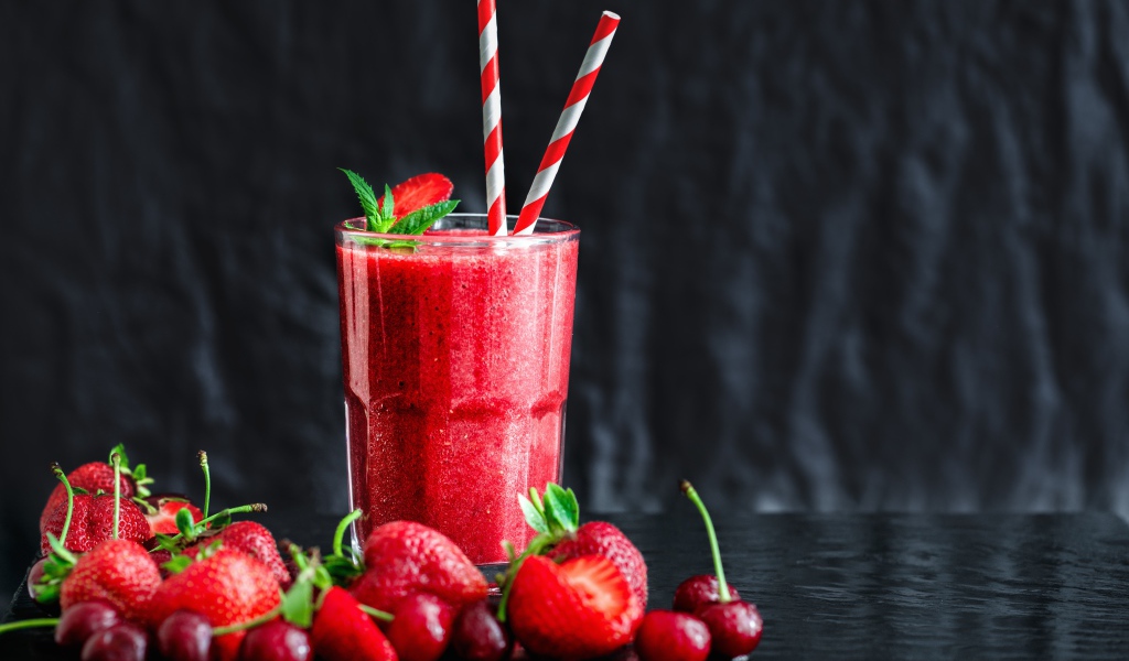 Смузи с ягодами клубники и вишни на столе