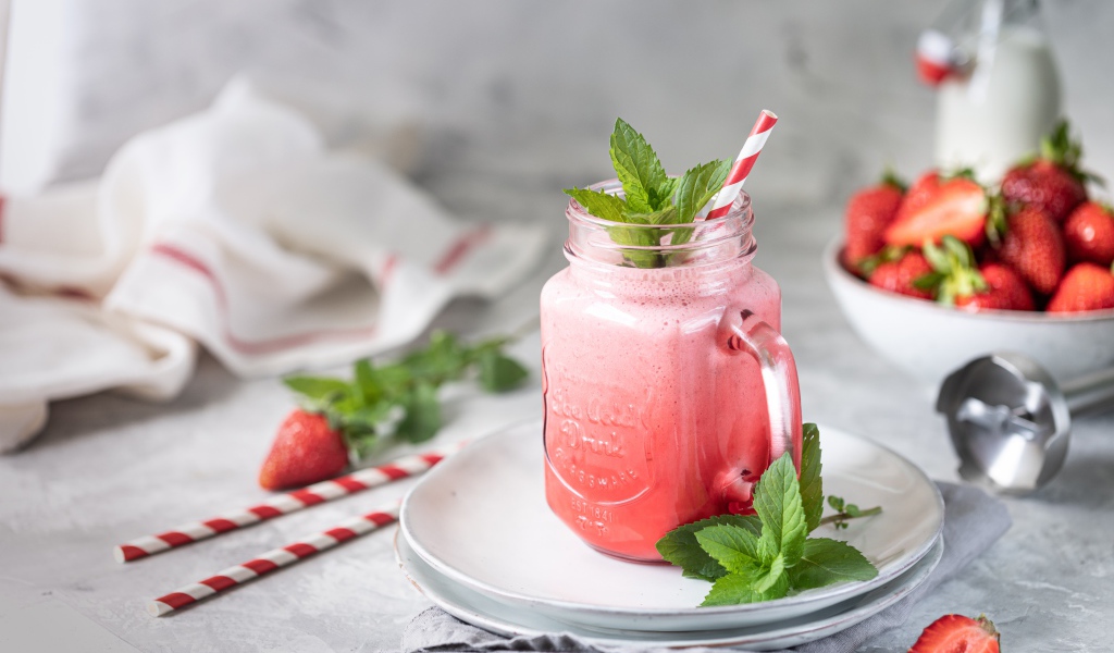 Смузи с клубникой в банке с трубочкой и листьями мяты