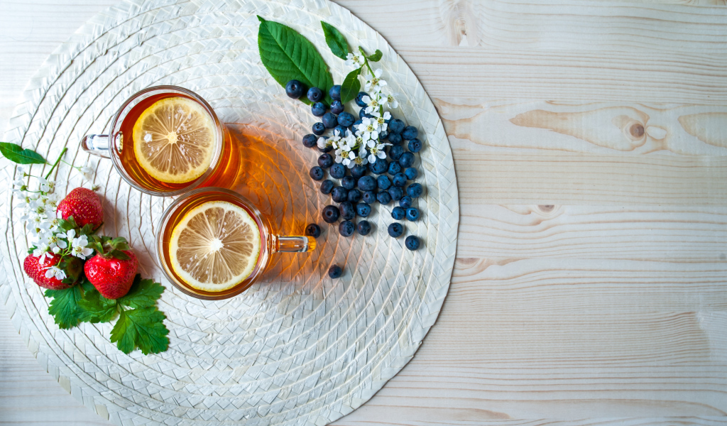 Чай с лимоном на столе с ягодами клубники и черники