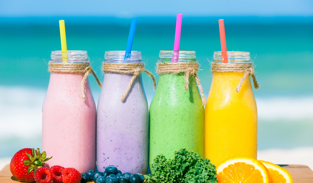 Три бутылочки со смузи на столе на пляже