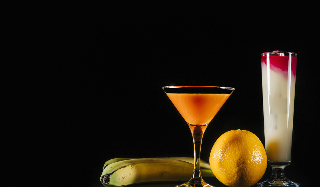 Два коктейля на черном фоне в бананом и апельсином