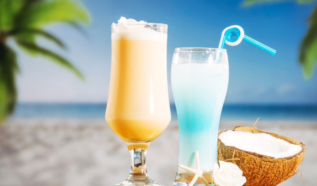 Два коктейля с кокосом на столе на тропическом пляже