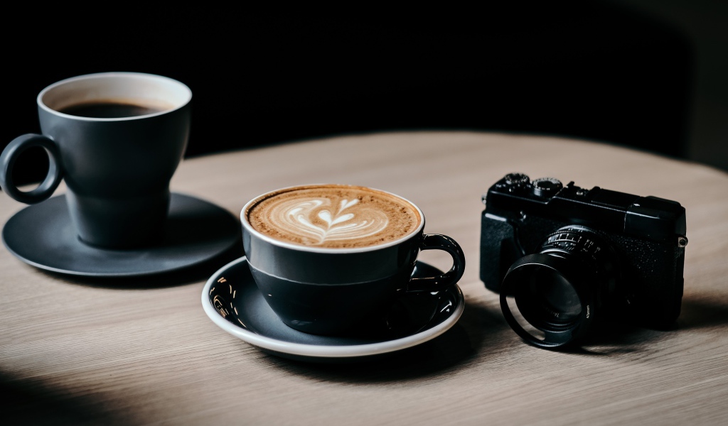 Две чашки кофе на столе с фотоаппаратом 