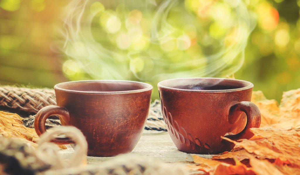 Два чашки горячего кофе с паром на столе осенью 