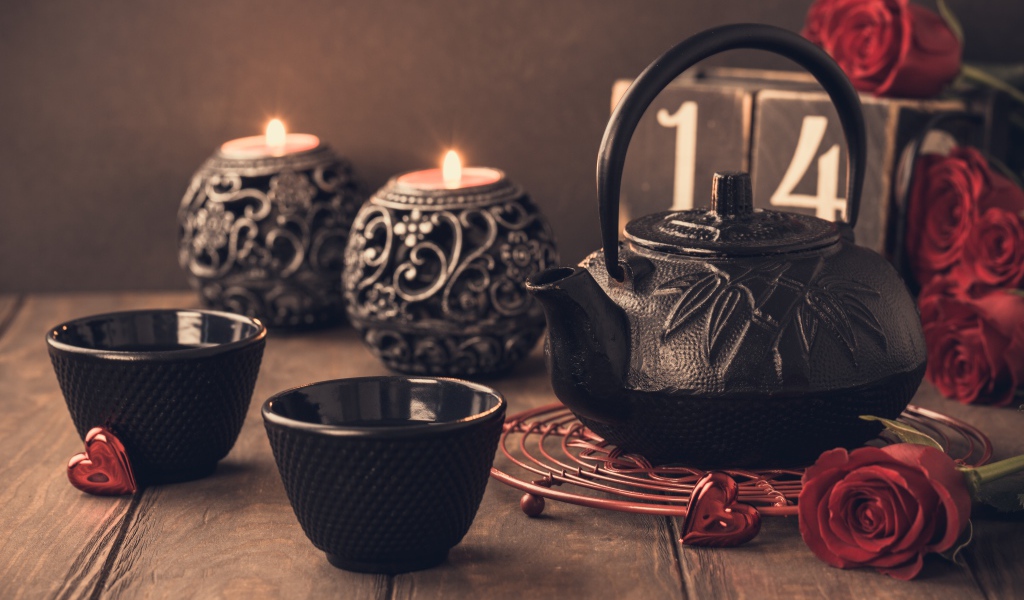 Две чашки чая на столе со свечами и красными розами