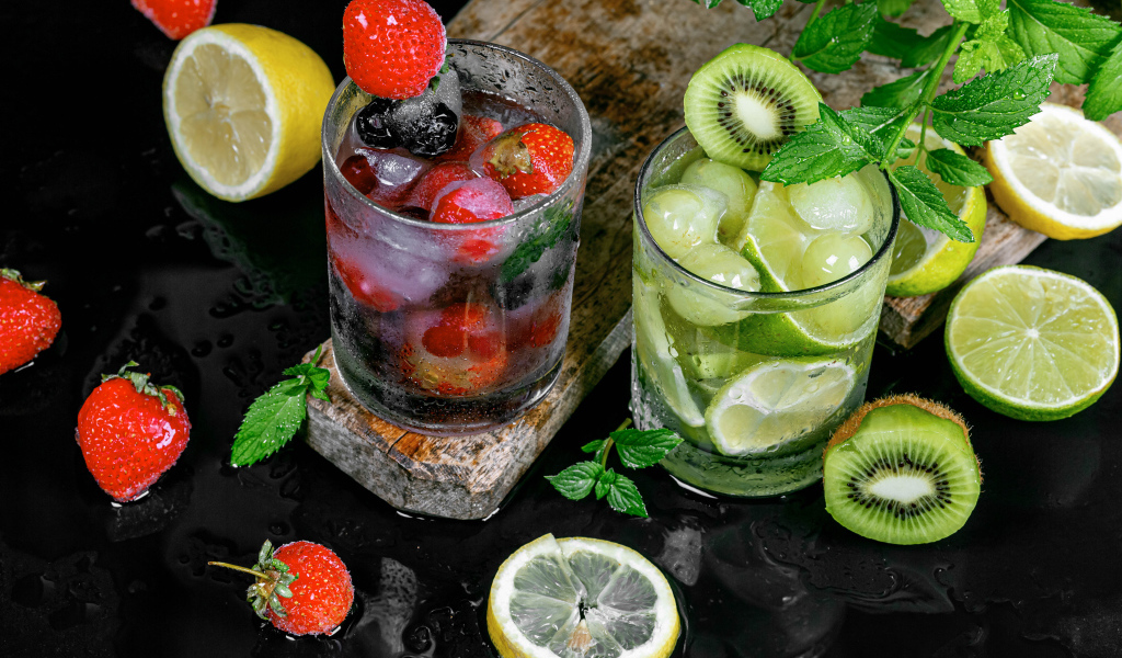 Два стакана мохито на столе с мятой, лимоном и клубникой 