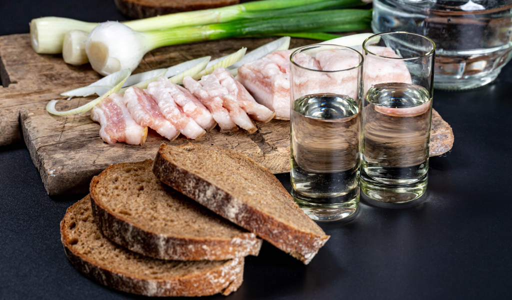 Две рюмки водки на столе с аппетитной закуской 