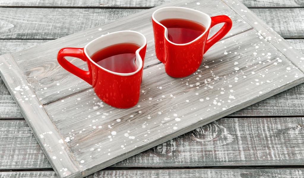 Две красные чашки в форме сердца на столе 