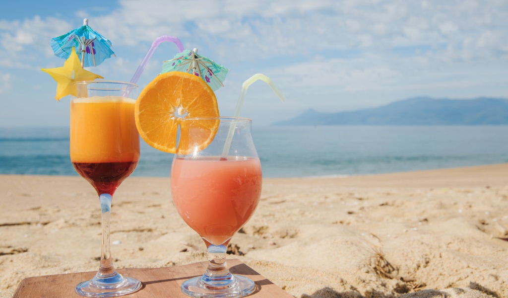 Два тропических коктейля на пляже в лучах солнца