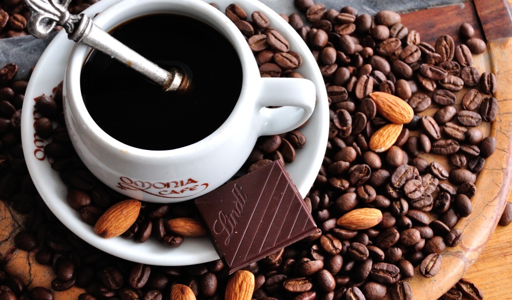 Белая чашка кофе на столе с кофейными зернами 