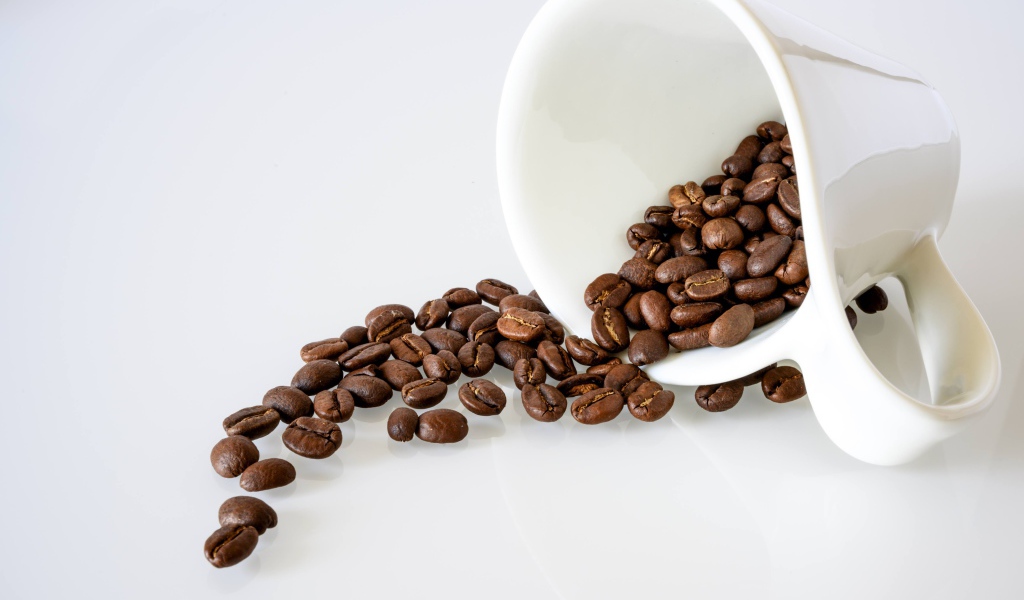 Белая чашка с кофейными зернами на белом фоне