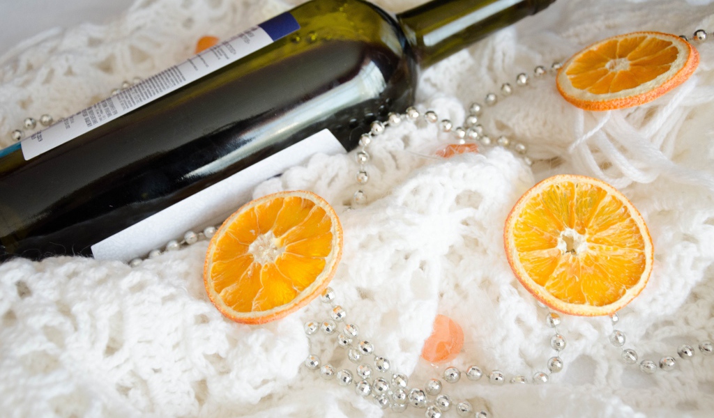 Бутылка вина и кусочки апельсина на белом платке 