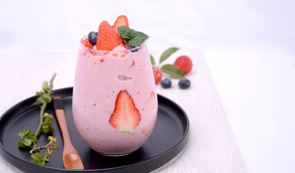 Йогурт в стакане с ягодами черники и клубники